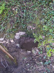 Close up of Kilkhampton Common spring. It is in need of repair as the surrounding brickwork is deteriorating. It is circular in shape.